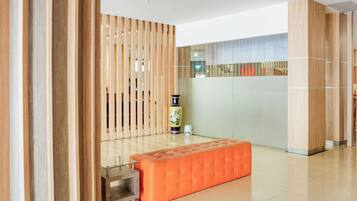 A modern lobby with a wooden partition, a glass partition, and a seating area with a cushioned bench.