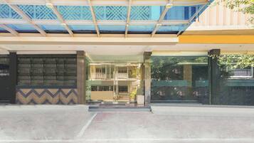 A building entrance with a glass facade, a patterned wall, and a metal roof structure.