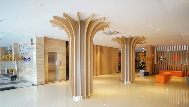Un vestíbulo de hotel moderno con fachada de vidrio, una recepción y un árbol de Navidad.