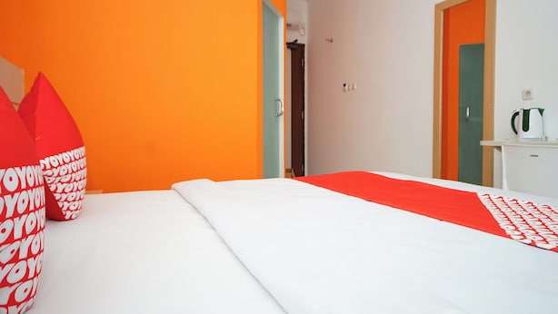 Quarto de hotel com uma cama, travesseiro e colcha estampados em vermelho e branco.