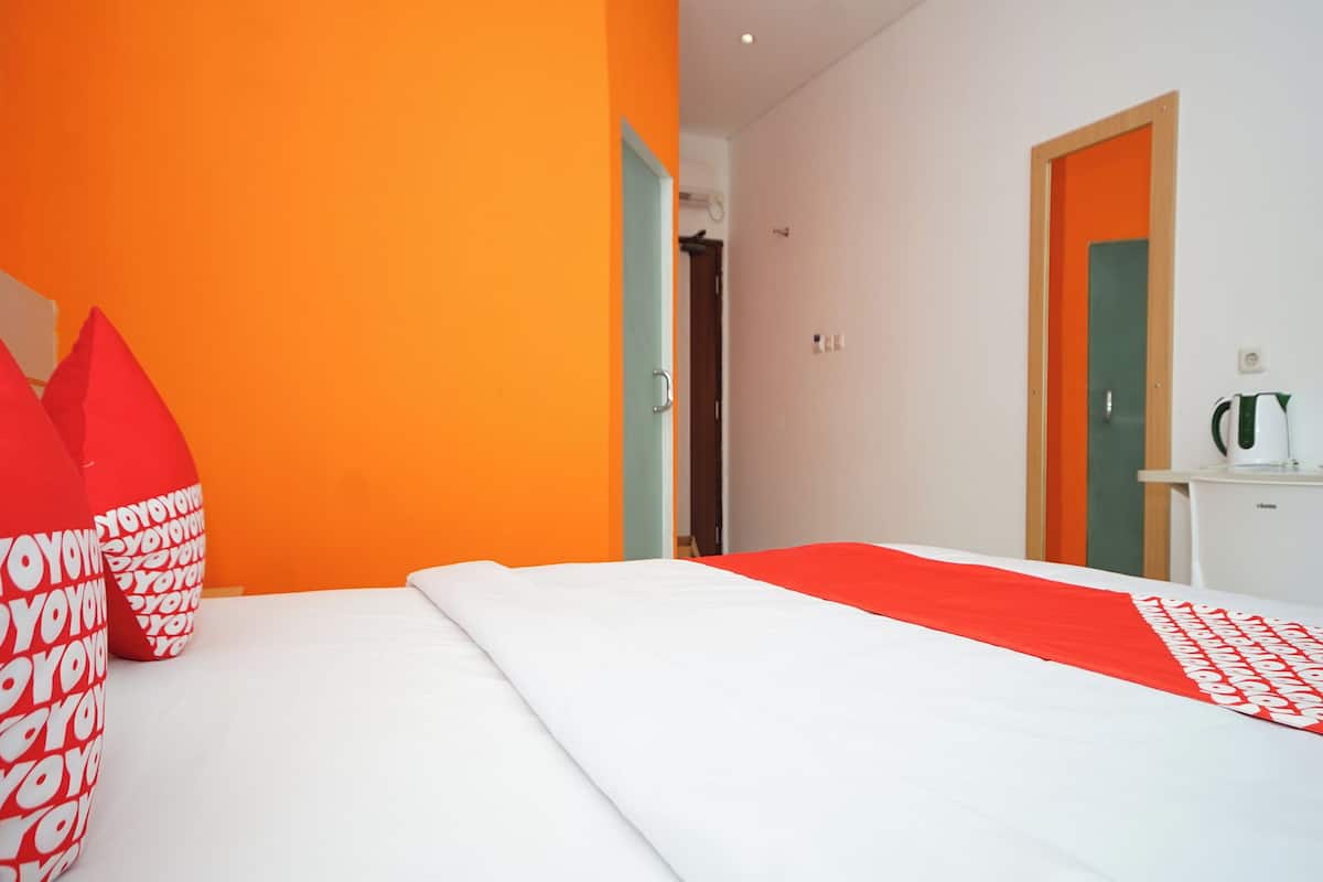 Quarto de hotel com uma cama, travesseiro e colcha estampados em vermelho e branco.