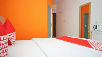 A hotel room with a bed, a red and white patterned pillow, and a red and white bedspread.