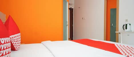Habitación de hotel con una cama, almohada y colcha con estampado rojo y blanco.