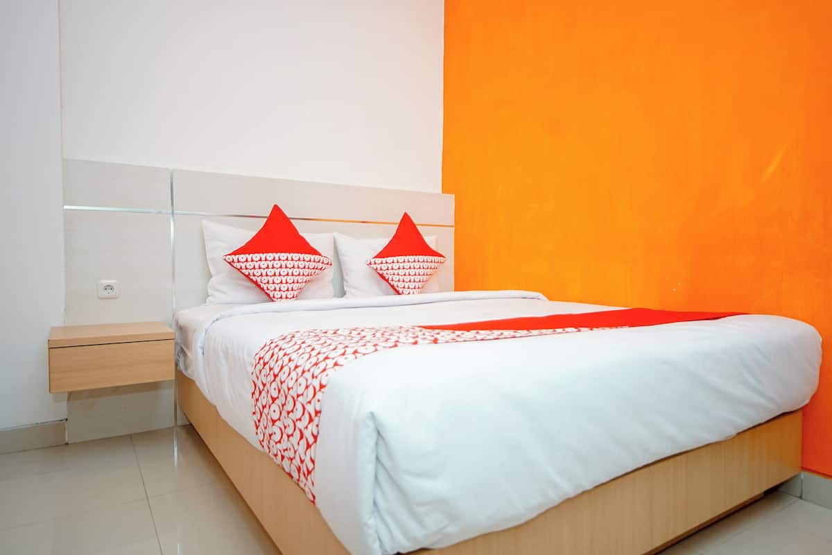 Um quarto moderno com uma cama, uma mesa de cabeceira e uma parede de destaque laranja vibrante.