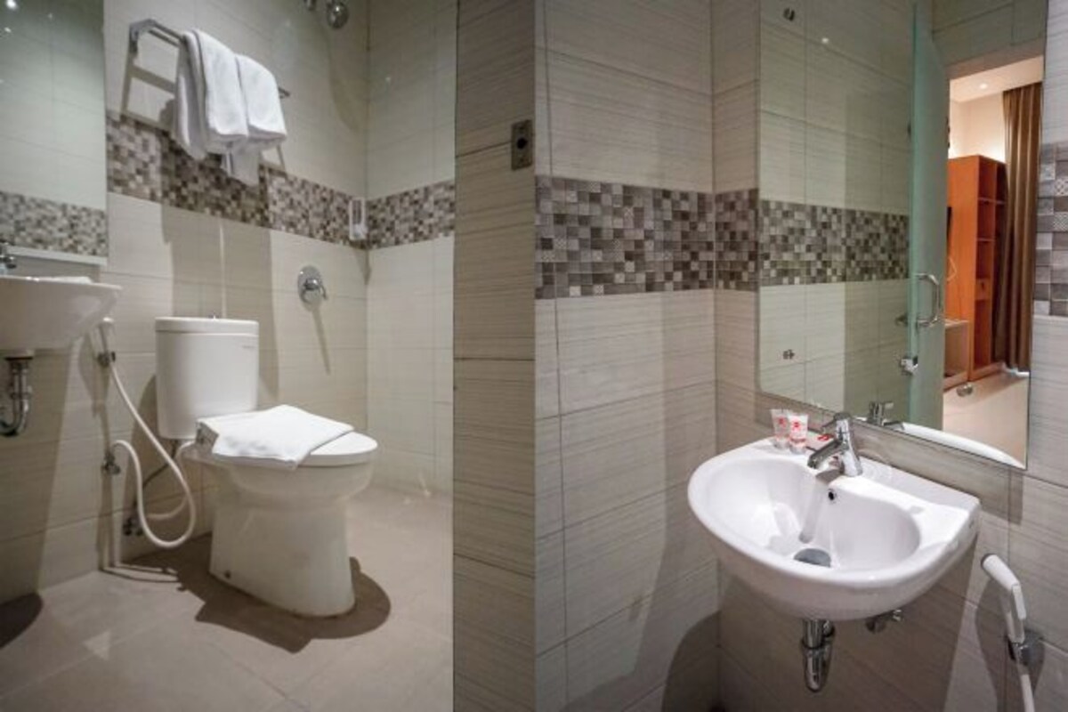 A bathroom with a toilet, sink, and mirror.