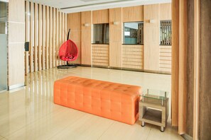 A spacious room with a large orange ottoman, a red hanging chair, and a glass coffee table. - Townhouse Oak Palembang near Palembang Golf Club formerly KR Hotel (Palembang)