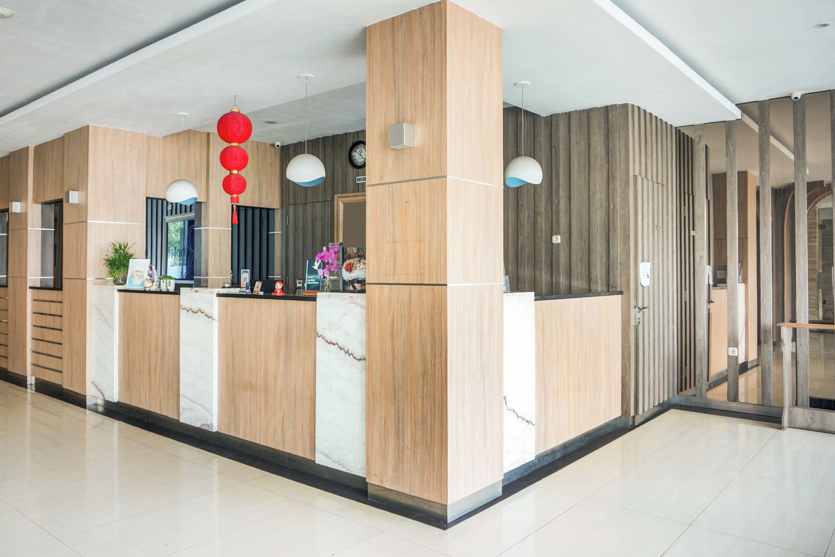 A reception area with a marble counter, wooden paneling, and a clock on the wall.
