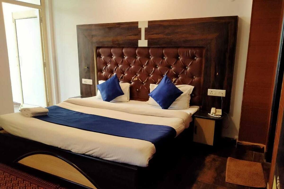 Un letto ben rifatto con testiera capitonata, due cuscini e un comodino con una lampada.
