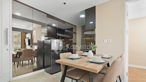 Una cocina moderna con refrigerador incorporado, una mesa de comedor con platos y tazas, y vista al área de comedor.