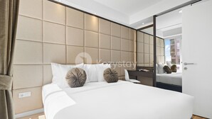 Habitación de hotel moderna con una cama grande, un cabecero acolchado y un espejo amplio.