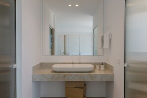 Un baño moderno con un espejo grande, un lavabo blanco y una encimera de mármol.
