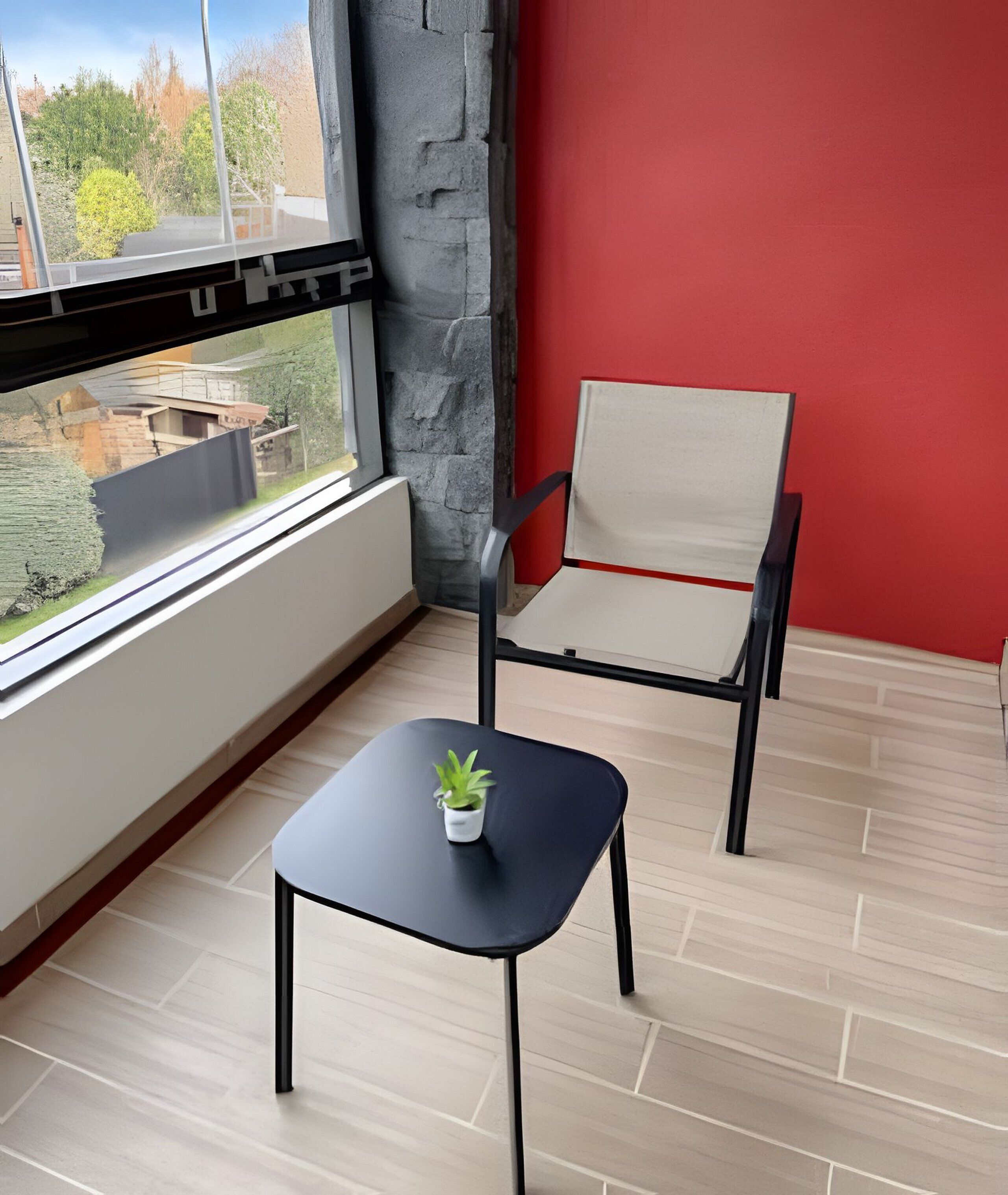 Un petit balcon avec une chaise noire et une petite table sur laquelle est posée une plante.