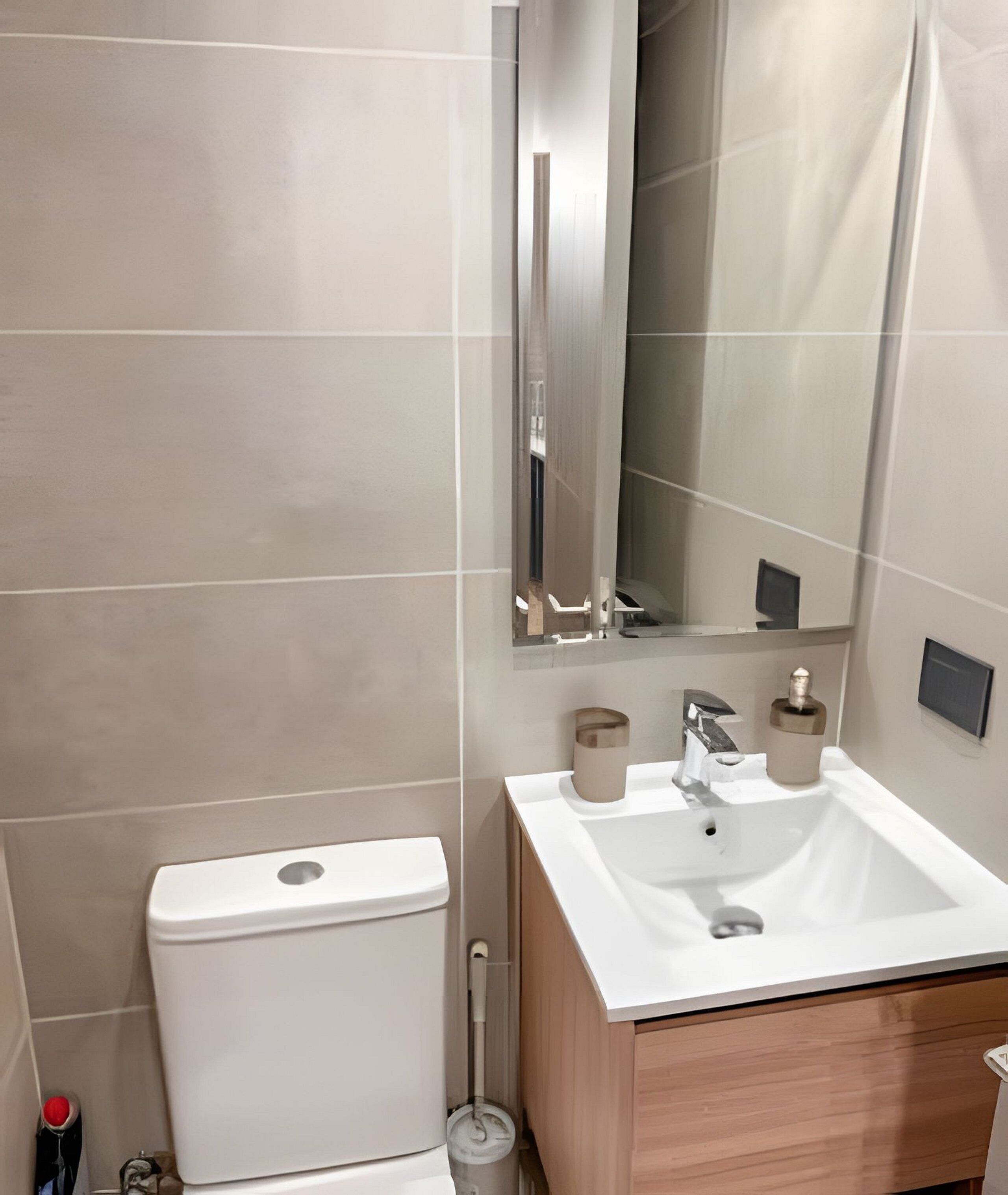 A modern bathroom with a white sink, a mirror, and a toilet.
