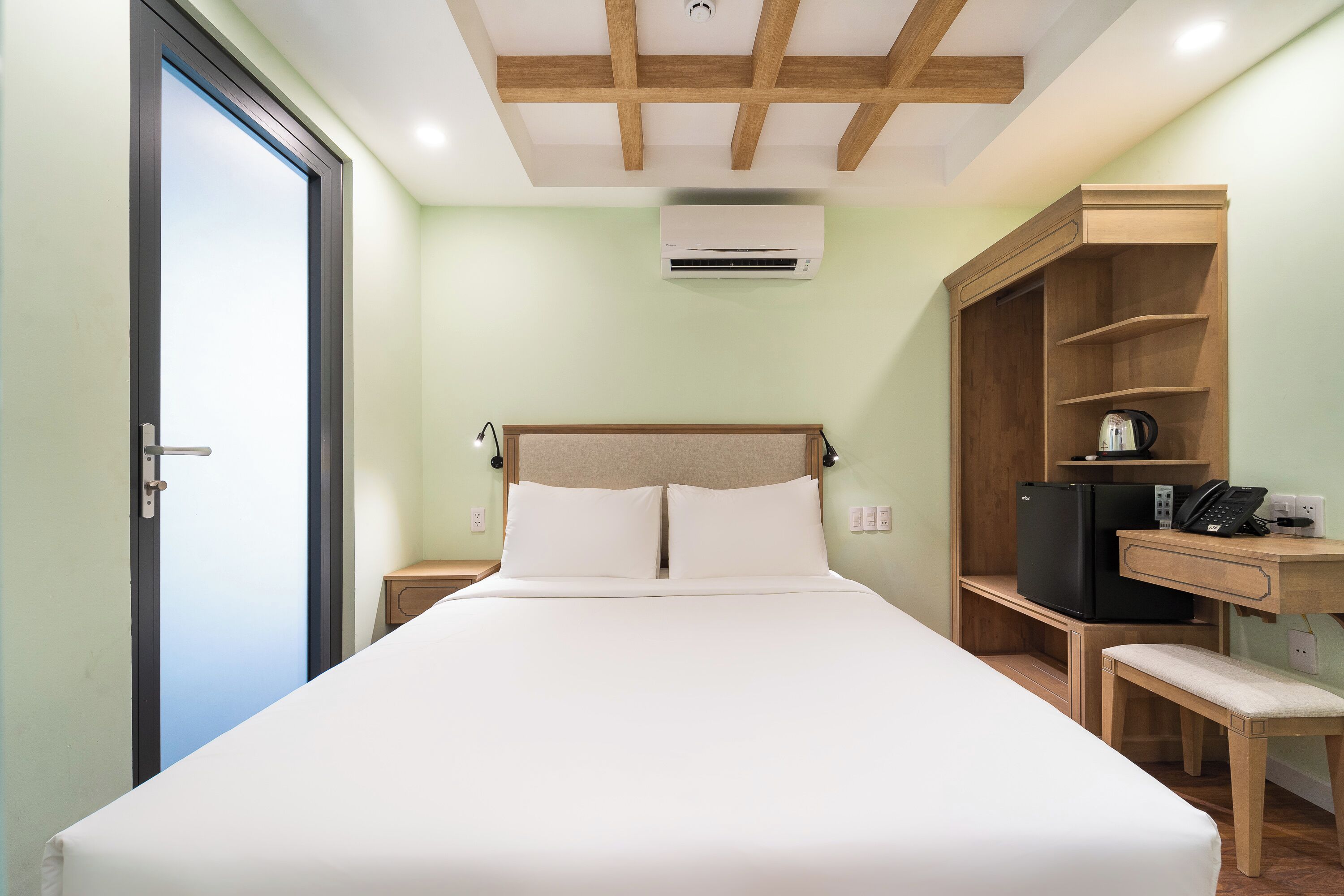 Une chambre d’hôtel équipée d’un lit, d’un bureau, d’une chaise, d’une armoire et d’un appareil de climatisation.
