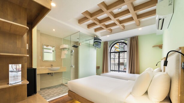 A modern hotel room with a wooden ceiling, a large bed with white bedding, a glass shower enclosure, and a view of the outside through a window with curtains. - Nicecy Hotel - Truong Quyen (Ho Chi Minh City)