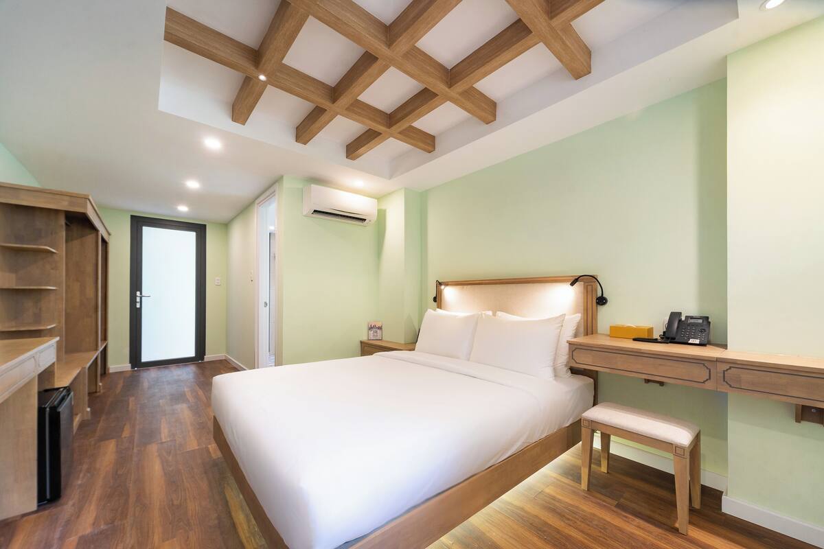 A bedroom with a wooden bed frame, a desk with a chair, and a bench.