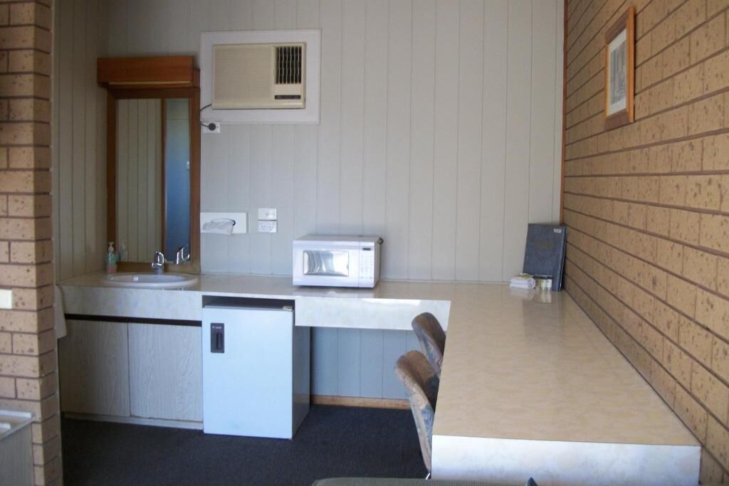 Una kitchenette compacta con pileta, microondas y heladera pequeña.