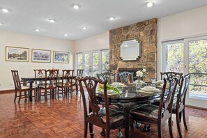 A dining room with a stone fireplace, large windows, and a herringbone wood floor. - Historic Souther Country Inn - 11 BR Lodge Perfect for Get Togethers! (Blairsville)