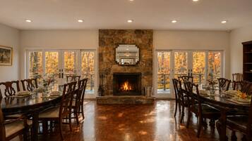 A dining room with a stone fireplace, wooden chairs, and a table set for four.