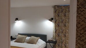 A bedroom with a bed, bedside lamps, a nightstand, and a patterned curtain. - Bed and breakfast in southern Corsica near dream beaches (Sotta)
