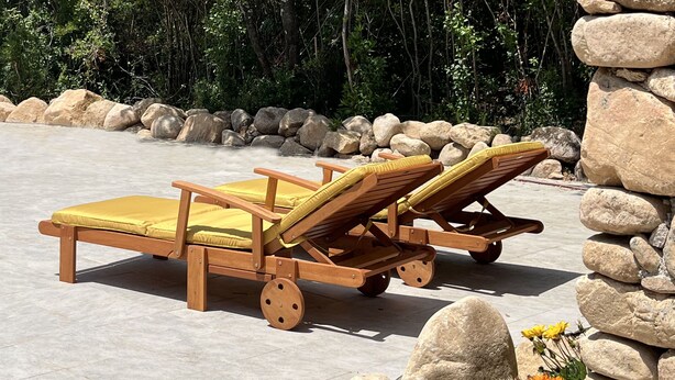 Two wooden lounge chairs with yellow cushions, positioned on a tiled patio with a stone wall and a garden with flowers. - Bed and breakfast in southern Corsica near dream beaches (Sotta)
