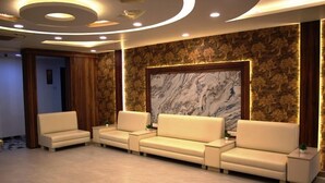 A reception area with a sofa set, a marble accent wall, and a wooden panel design. - Hotel jageshwari inn (Gwalior)