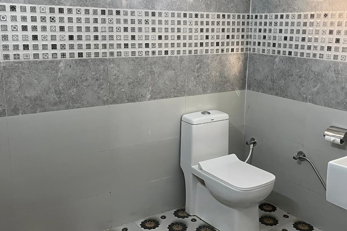 Un baño con inodoro, bidé y una ventana pequeña.