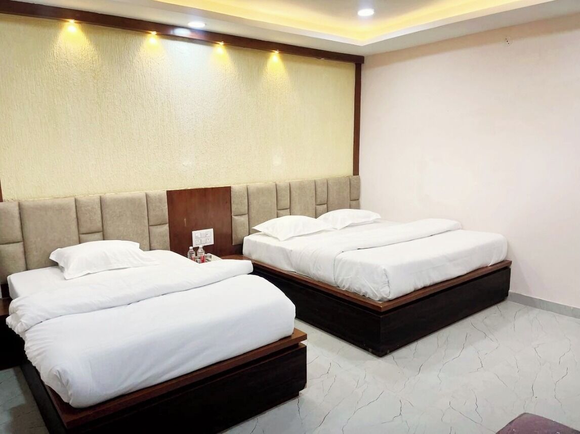 A hotel room with two beds, a wooden headboard, a white wall, and a marble floor.