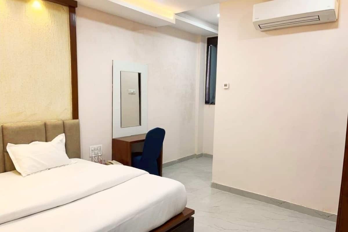 Una habitación de hotel con una cama, un escritorio y un equipo de aire acondicionado.