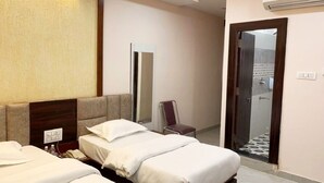 A hotel room with two beds, a mirror, a chair, and an air conditioning unit. - Hotel jageshwari inn (Gwalior)