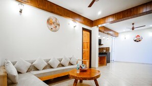 A living room with a sofa, a wooden coffee table, and a door leading to another room.