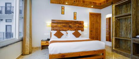 A bedroom with a wooden bed, a nightstand, a wooden wardrobe, and a large window.