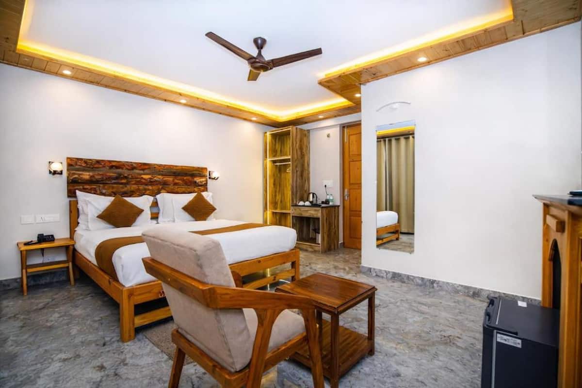 A bedroom with a wooden headboard, a bed with white linens, a wooden chair, a small table, a ceiling fan, and a desk with a chair.