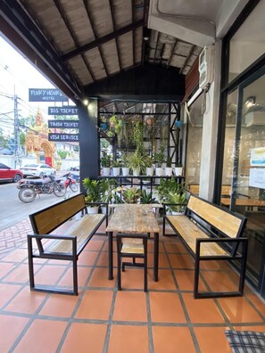 An outdoor seating area with benches and tables, surrounded by potted plants. - Funkymonkey Cafe&hostel (Vientiane)