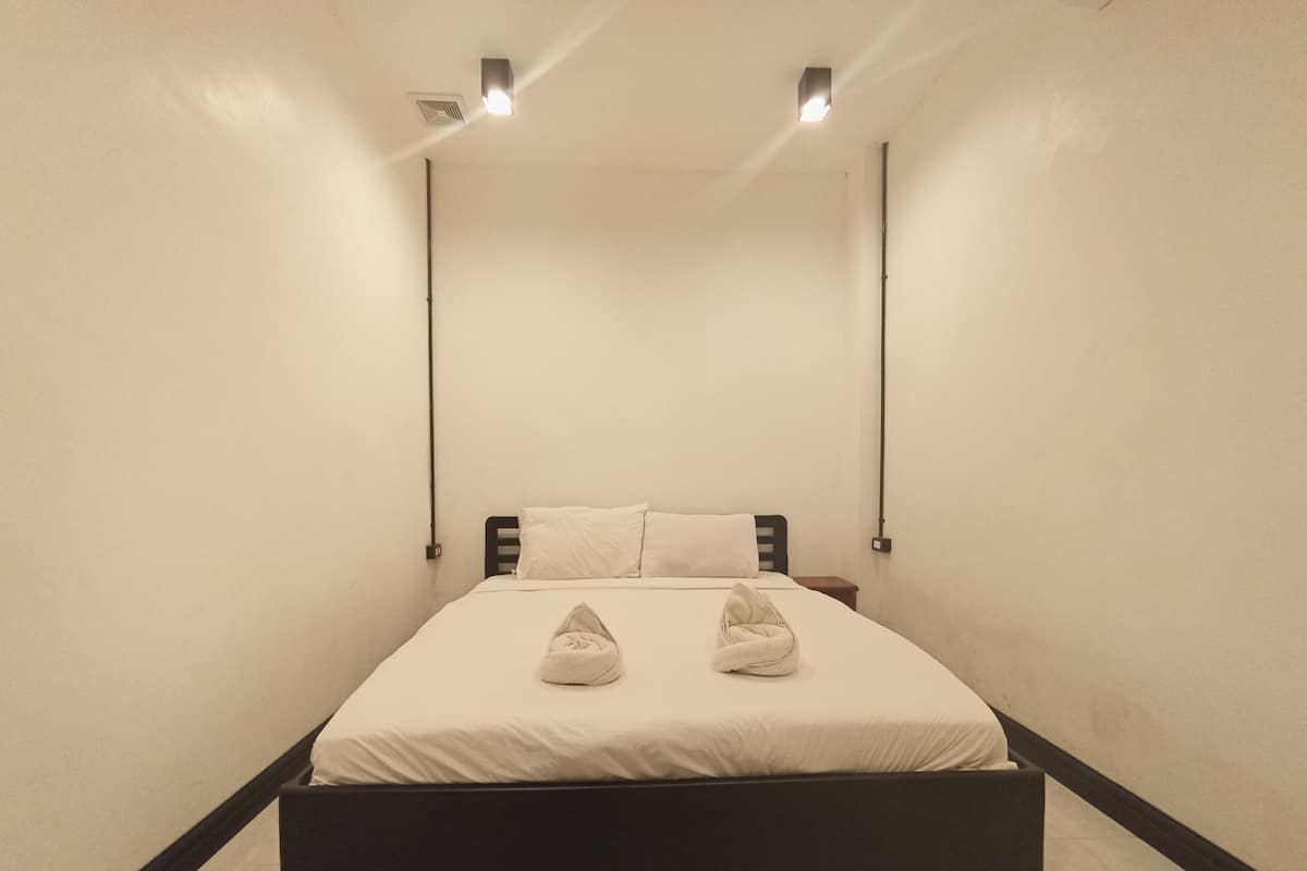 A minimalist bedroom with a bed, two bedside lamps, and a nightstand.