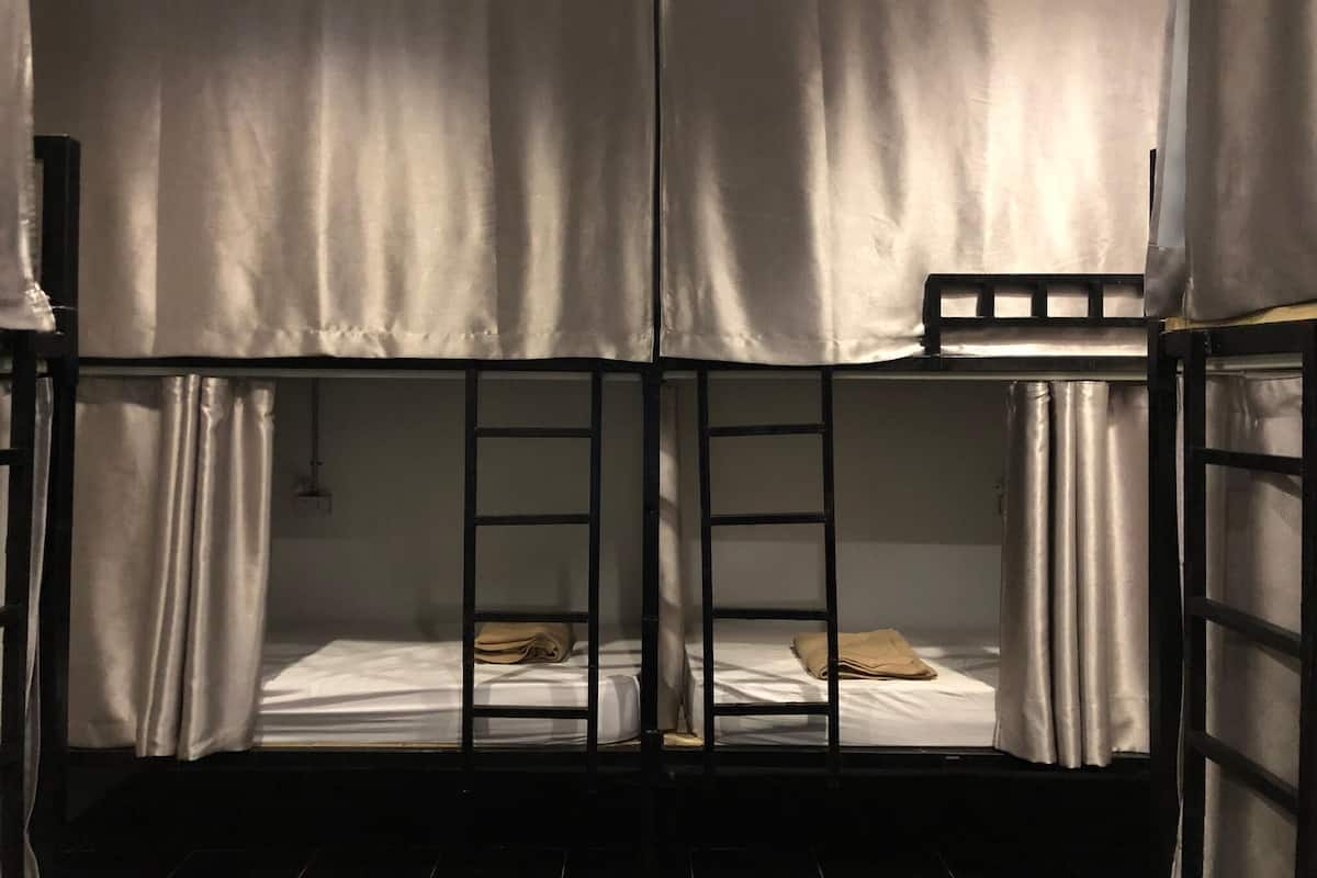 A bunk bed room with curtains, a ladder, and a bed with a pillow.