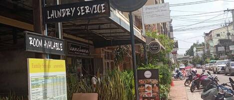 A building with signs for taxi service, motorbike for rent, laundry service, and room availability.