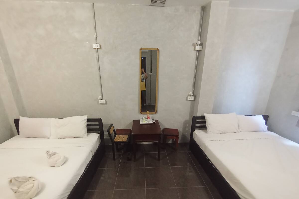 A hotel room with two beds, a desk, and a mirror.