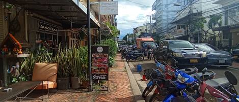 A street with a brick sidewalk, parked motorcycles, and a building with a sign reading "Pimenton".
