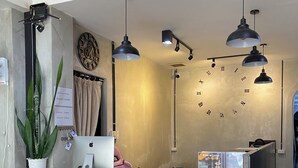 A reception desk with a laptop, a plant, and a clock on the wall. - Funkymonkey Cafe&hostel (Vientiane)