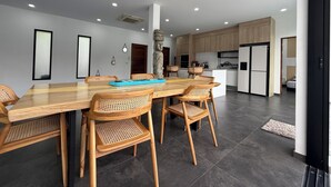 Un comedor moderno con una mesa de madera y sillas de ratán, una cocina con armarios de madera y una escultura de piedra.