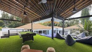 Un área de descanso al aire libre con césped artificial, una mesa de billar y asientos cómodos.