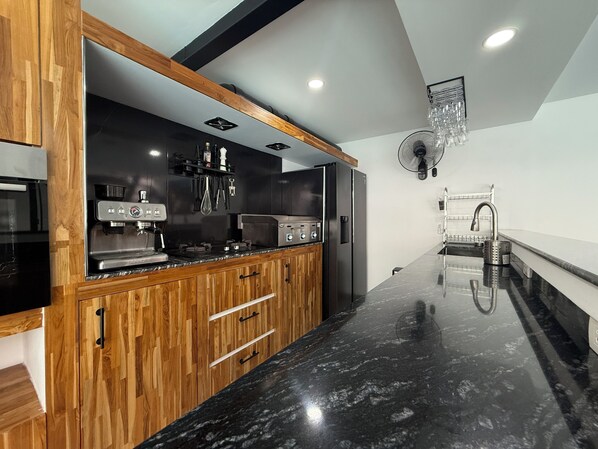 A modern kitchen with wooden cabinets, a black countertop, and stainless steel appliances.