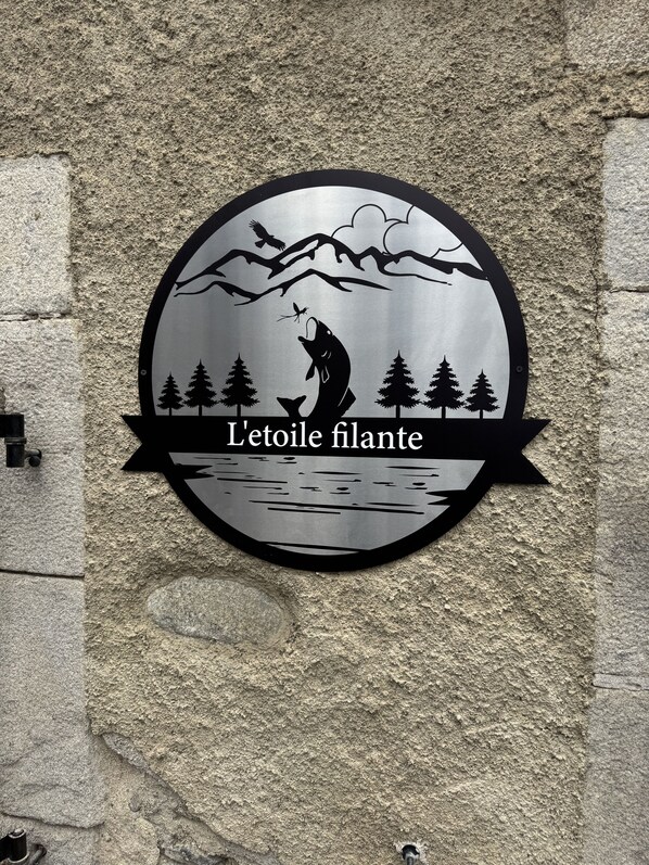 A circular sign with a silhouette of a person fishing, trees, and mountains. - C'est dans notre Cocoon face au coeur du Village de formiguere. (Formiguere)