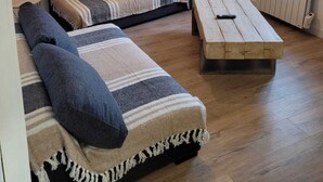A cozy living room with a sofa, a wooden coffee table, and a hanging light fixture. - C'est dans notre Cocoon face au coeur du Village de formiguere. (Formiguere)