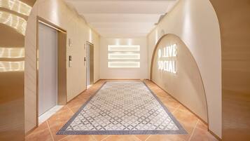 A hallway with a patterned rug, a reception area with a 'Welcome' sign, and an elevator.