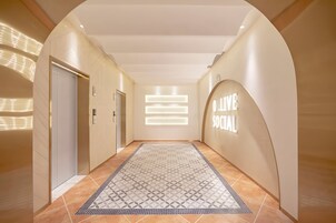 A hallway with a patterned rug, a reception area with a 'Welcome' sign, and an elevator.