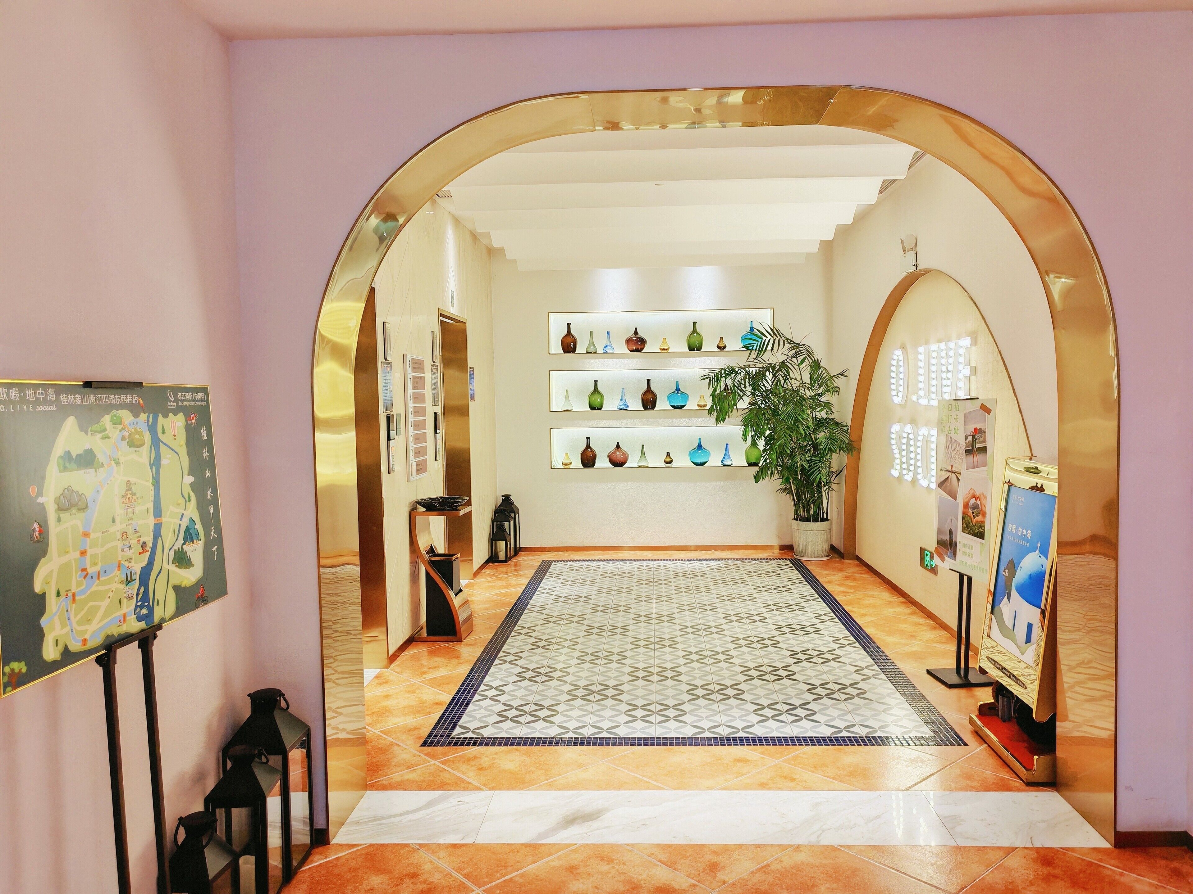 A hotel lobby with a central rug, a map on the wall, and shelves with decorative items.