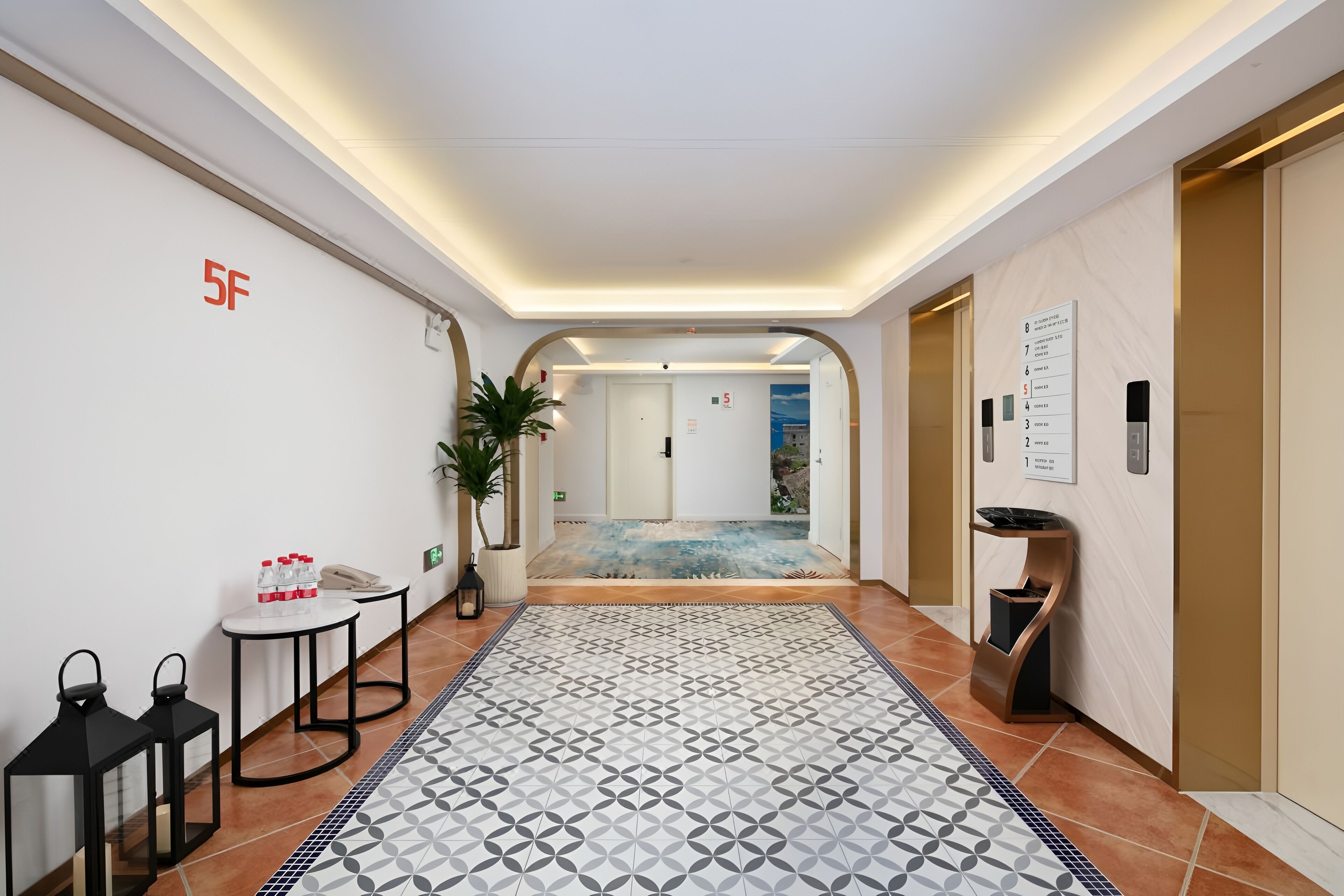 Un hall d’hôtel avec un sol carrelé, un comptoir d’accueil, une plante et un panneau indiquant le numéro de l’étage.