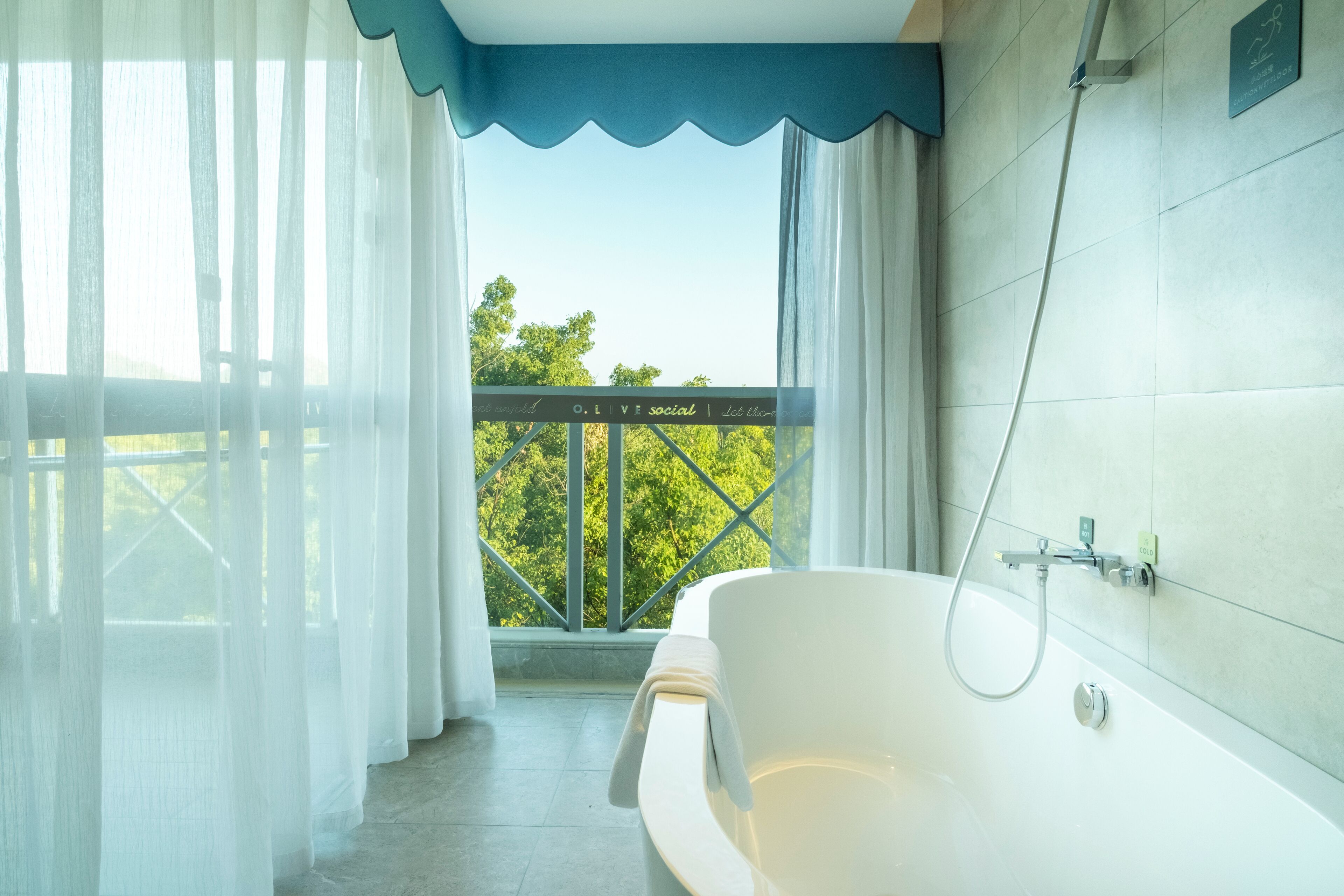 A bathroom with a bathtub, a shower, and a view of trees through a window.